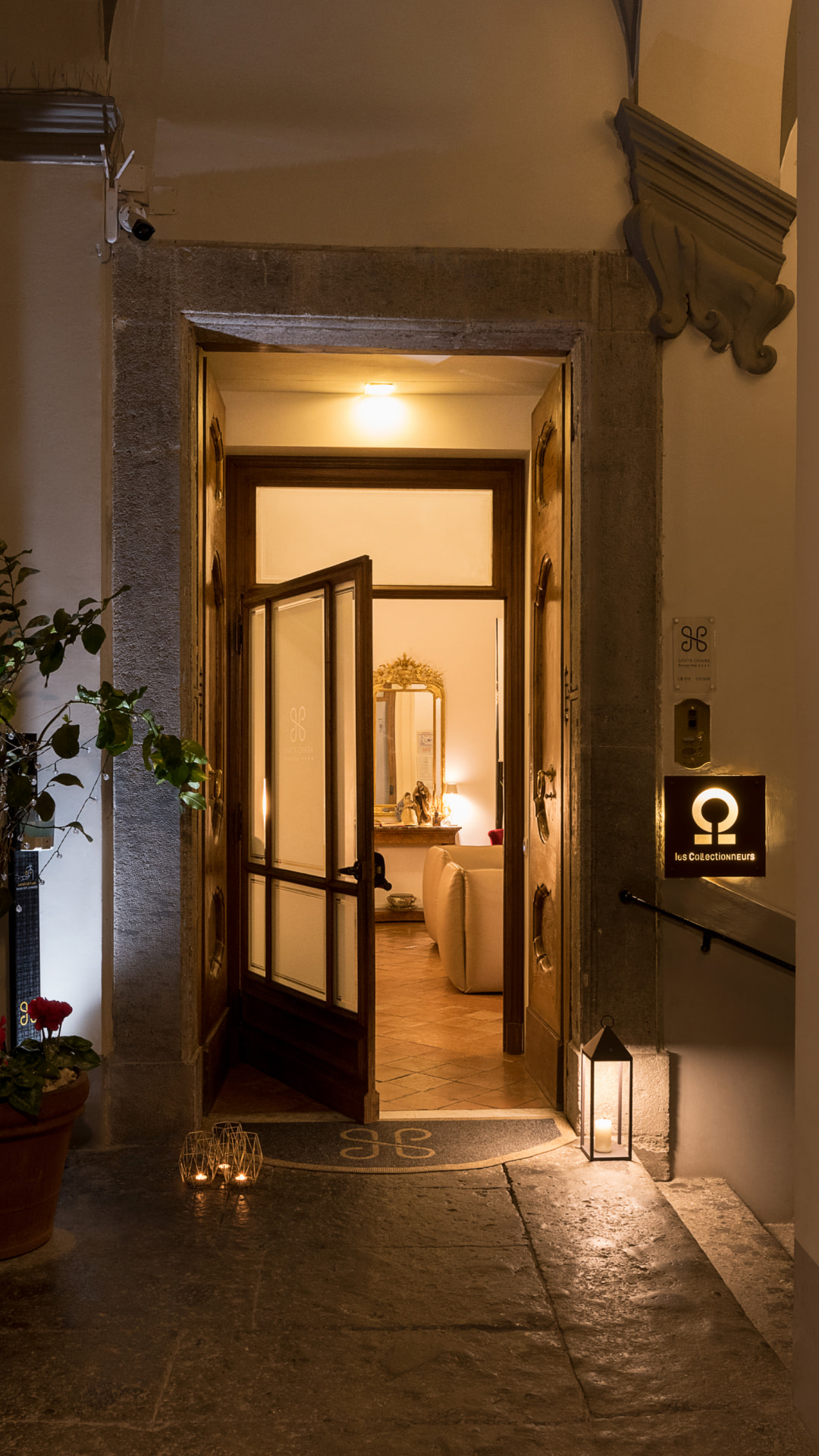 The illuminated entrance of the hotel, with the door open and a view of the interior.