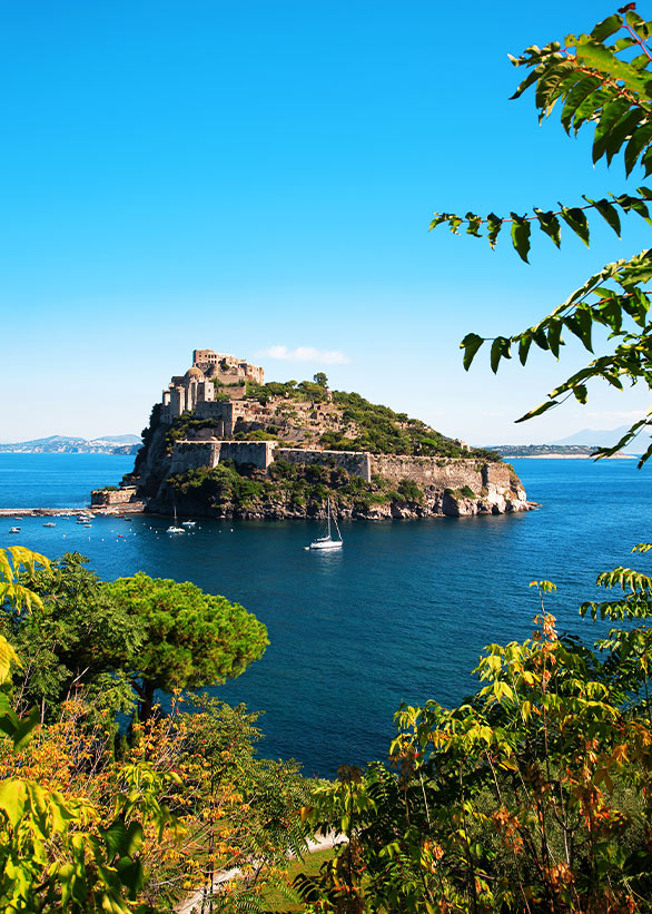Aragonese Castle of Ischia seen from the sea, surrounded by turquoise waters.