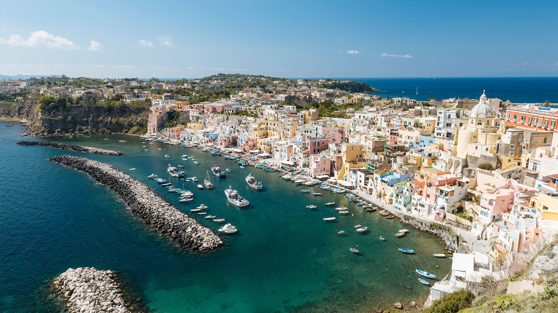 Panoramic view of Procida’s harbor with colorful houses and moored boats.